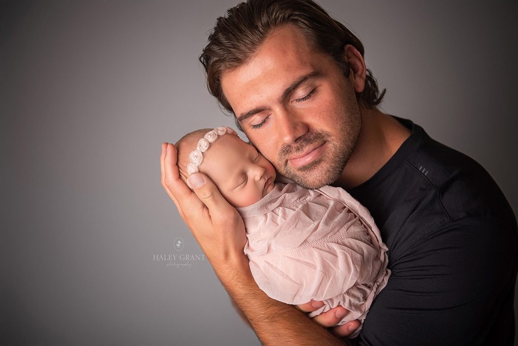 Dad holding his newborn baby girl. Photo taken at Haley Grant Photography, Cedar Park Texas Newborn Portrait studio.