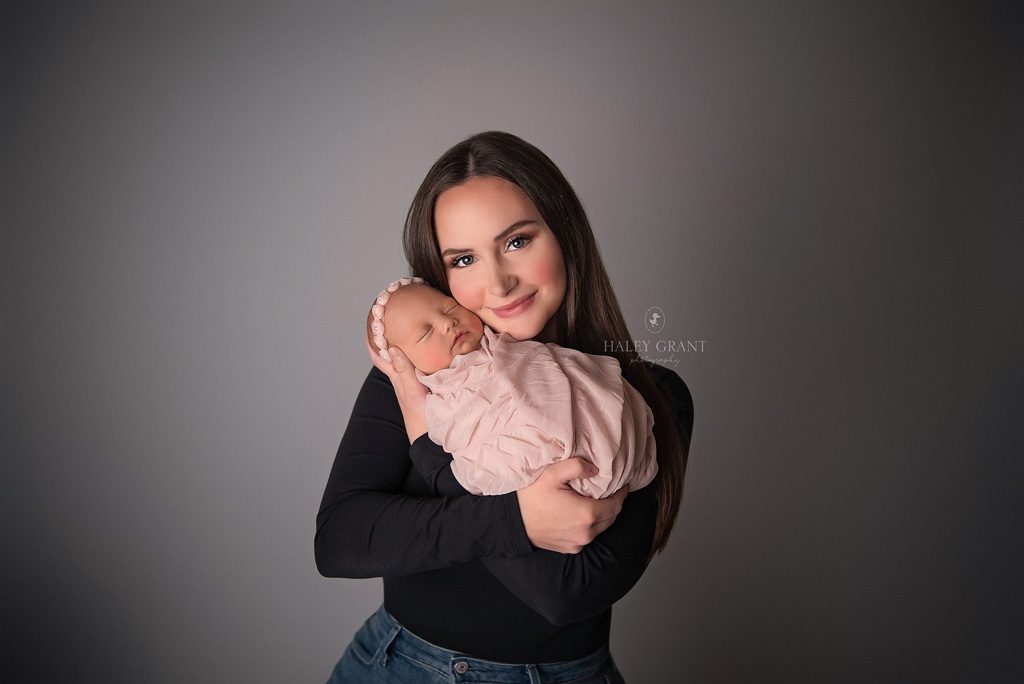 Mom holding her newborn baby girl. Photo taken at Haley Grant Photography, Cedar Park Texas Newborn Portrait studio.
