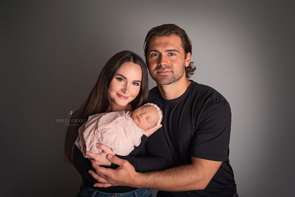 New parents holding their newborn baby girl Isla. Photo taken at Haley Grant Photography, Cedar Park Texas Newborn Portrait studio.